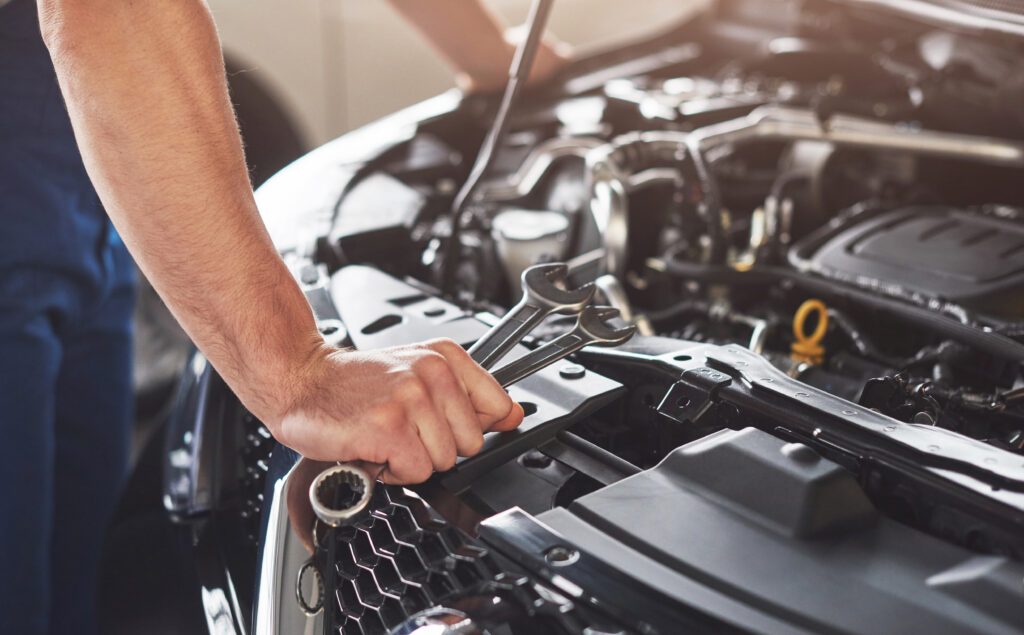 Mechanic carrying out an engine tune-up under the bonnet